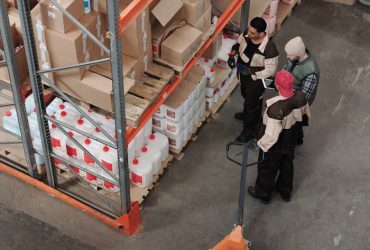 Three warehouse workers discussing inventory organization details.